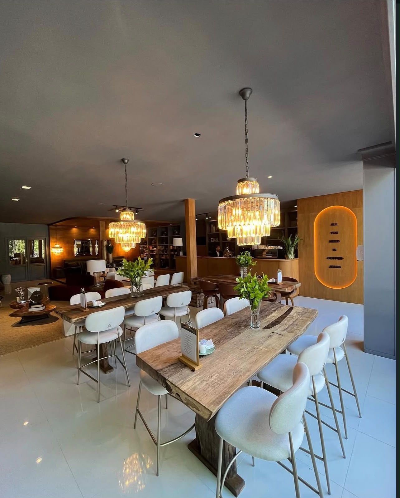 Salão interno da Semente Café e Livraria, com mesas comunitárias e iluminação aconchegante